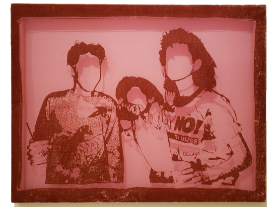 The photo captures a pink-hued fiber etching made of silk and rayon, depicting three young people in casual wear. One of them wears a t-shirt that prominently displays the slogan "Say No to Drugs!" The details of their faces aren't visible, leaving only their hair and the outline of their faces.