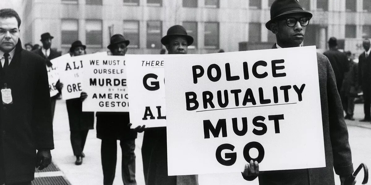 Black and white photograph of men protesting police brutality.